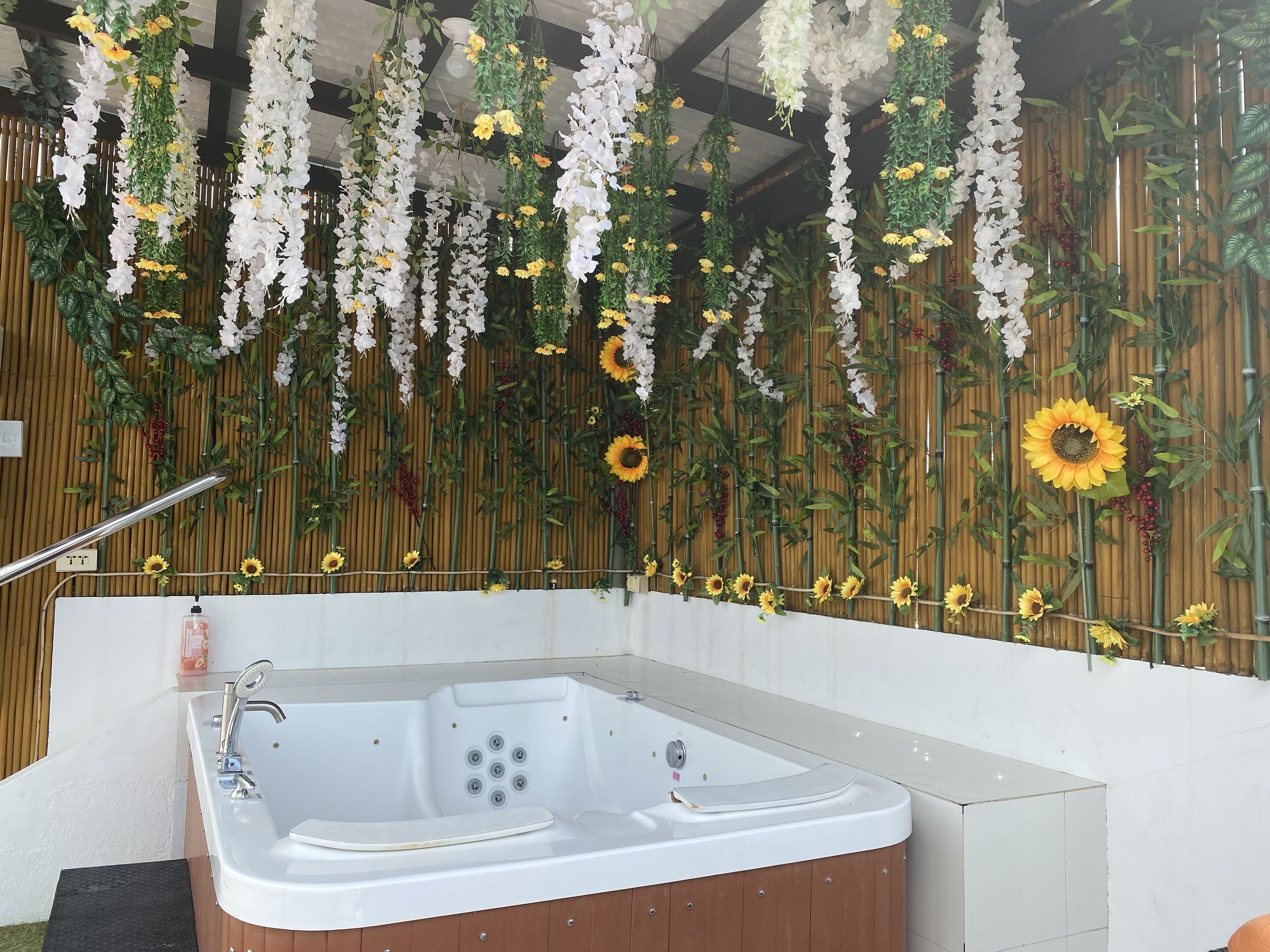 A spa area with a hot tub, bamboo wall decor, and hanging floral arrangements.