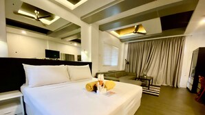 A modern hotel room with a large bed, a sofa, a TV, and a ceiling fan. - Lalaguna Villas Luxury Dive Resort & Spa (Puerto Galera)