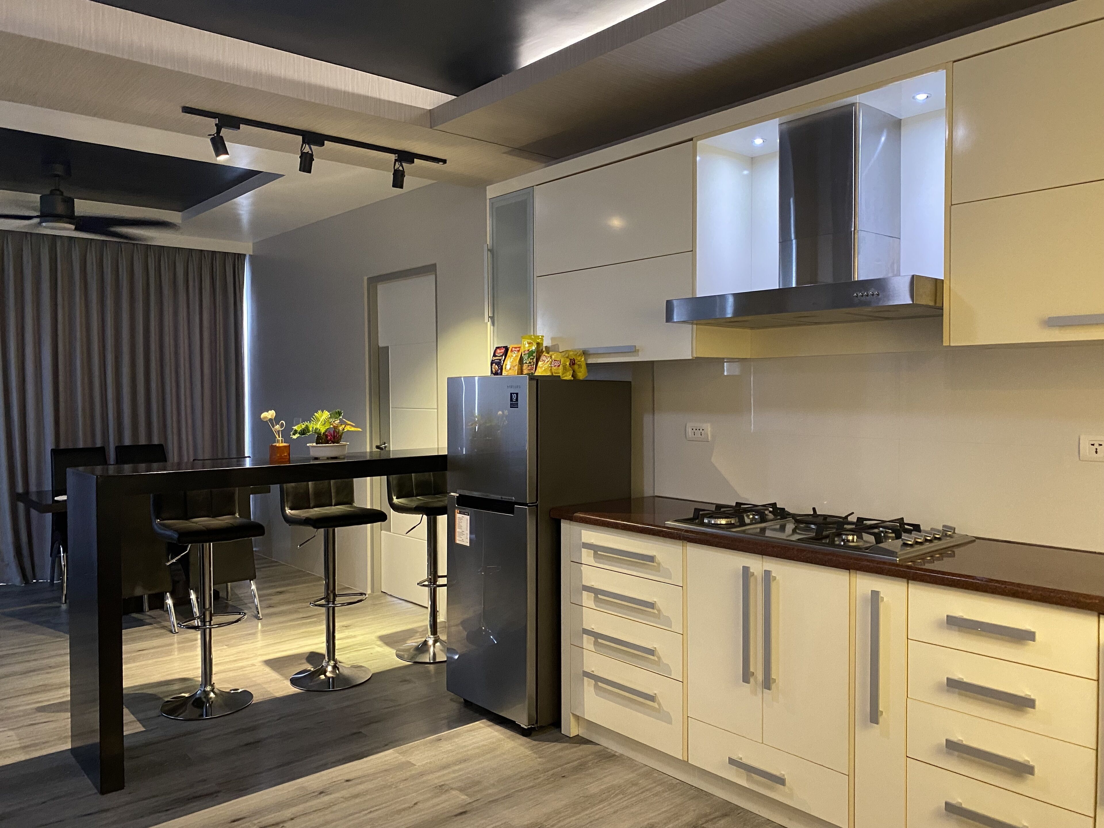 A modern kitchen with a central island, bar stools, stainless steel appliances, and a gas stove.