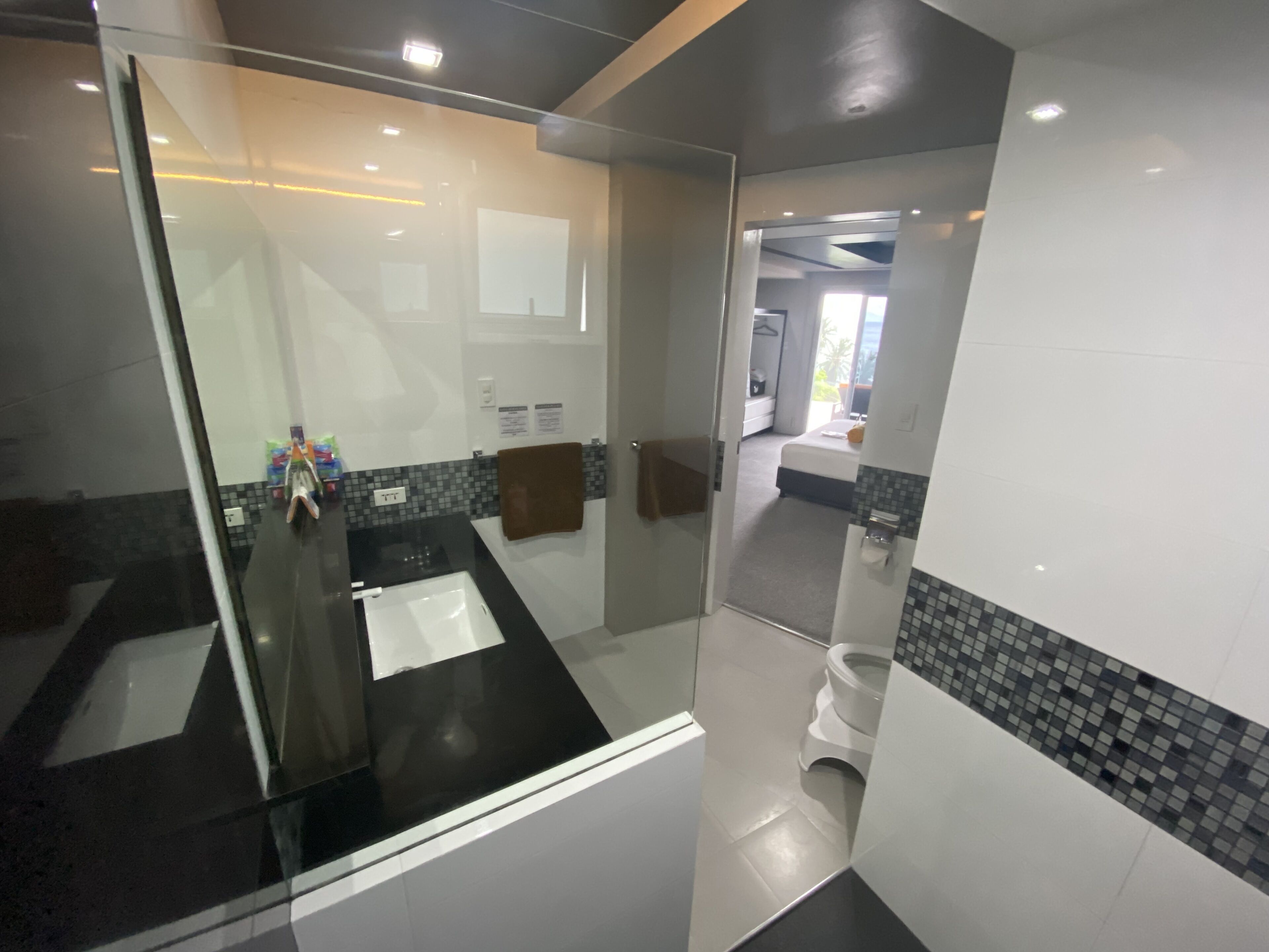 A modern bathroom with a glass shower enclosure, a black countertop, and a tiled backsplash.