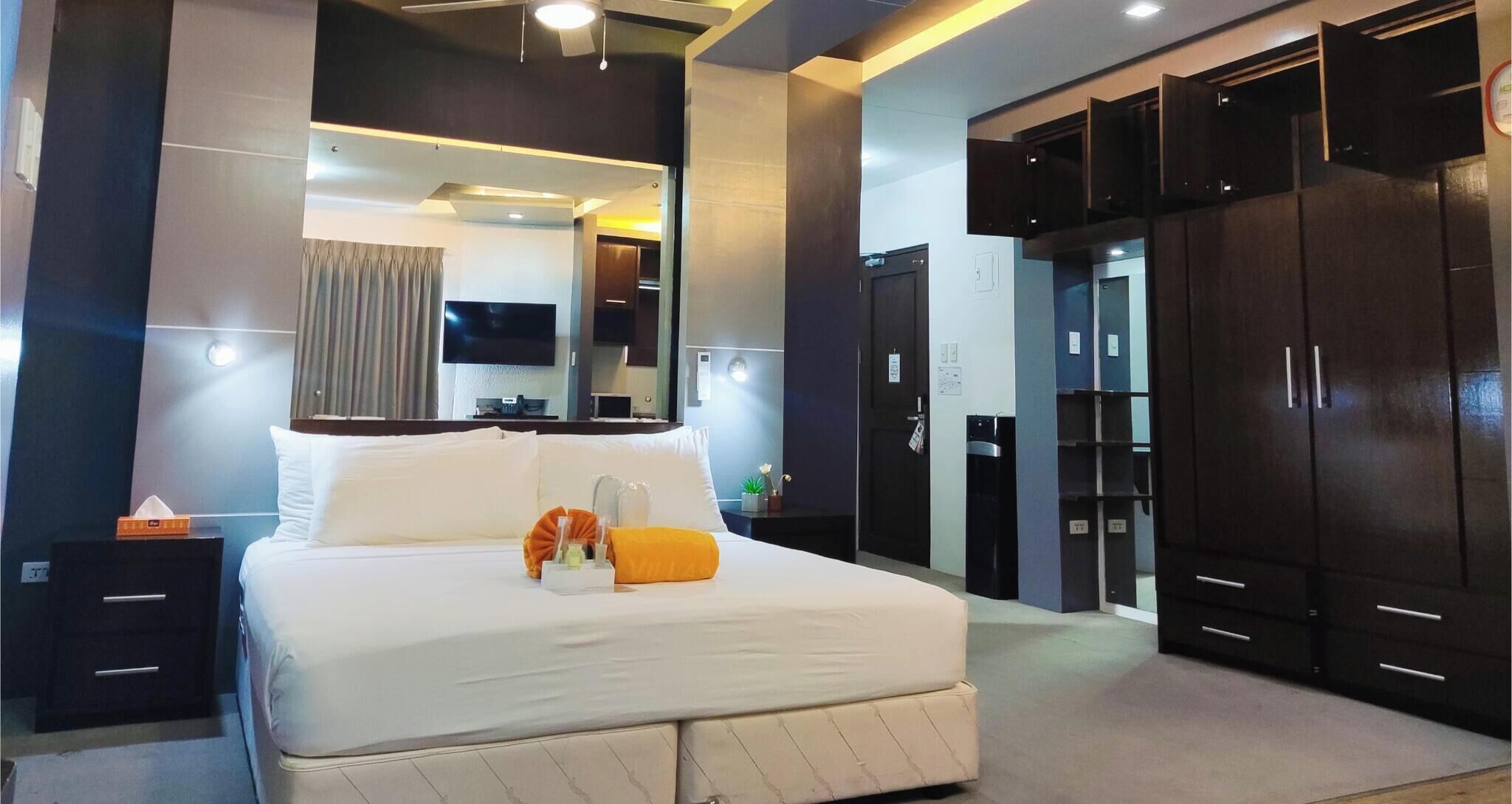 Een moderne hotelkamer met een groot bed, een flatscreen televisie, een bureau en een kledingkast.