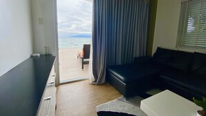 A modern living room with a black sofa, a white coffee table, and a view of the sea through a large window. - Lalaguna Villas Luxury Dive Resort & Spa (Puerto Galera)