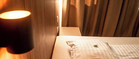 Ein Hotelzimmer mit Bett, Nachttischlampe und Vorhängen.