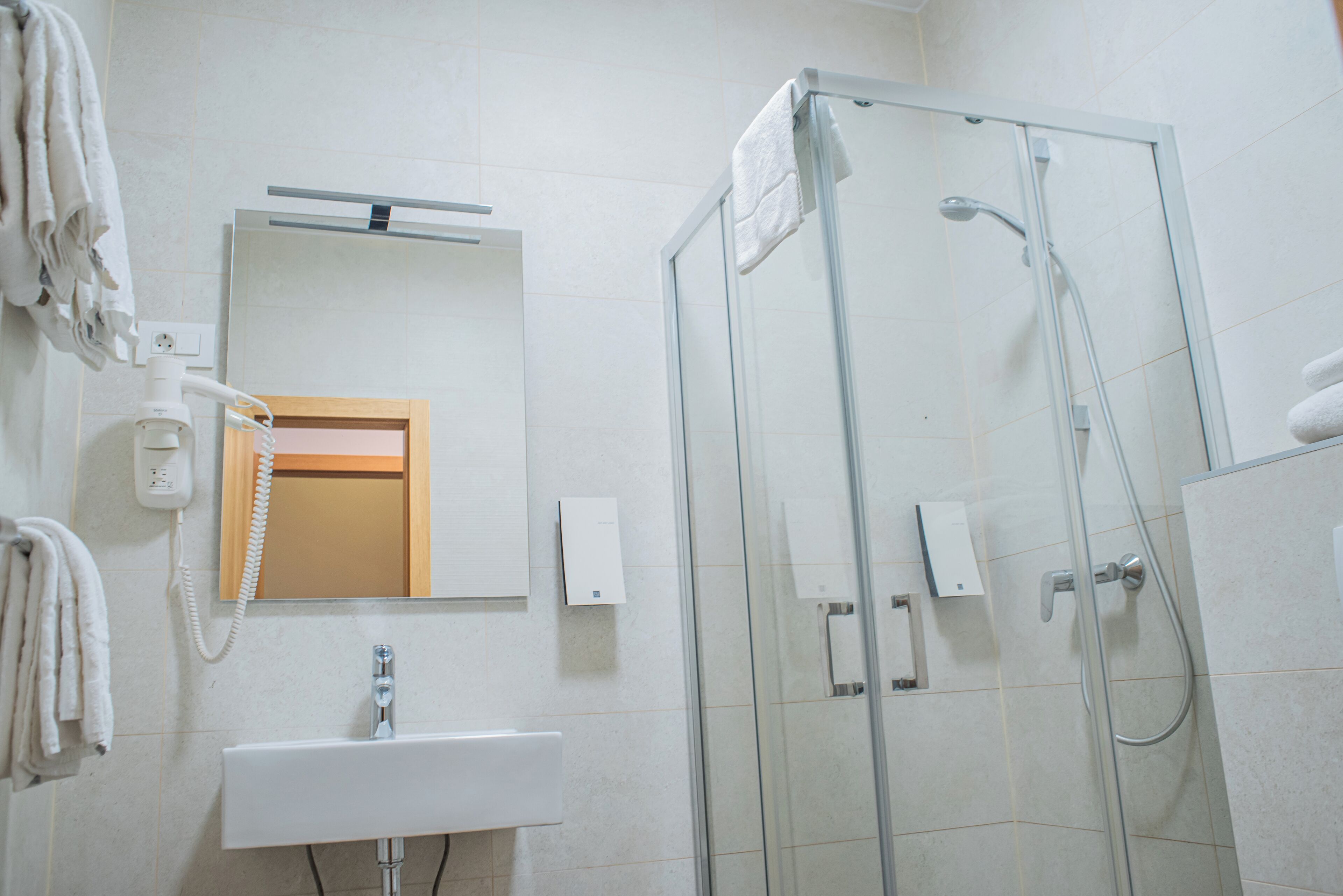 A modern bathroom with a glass-enclosed shower, a sink, a mirror, and a telephone.