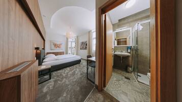 Una habitación de hotel moderna con cama, escritorio y baño con ducha y lavamanos.