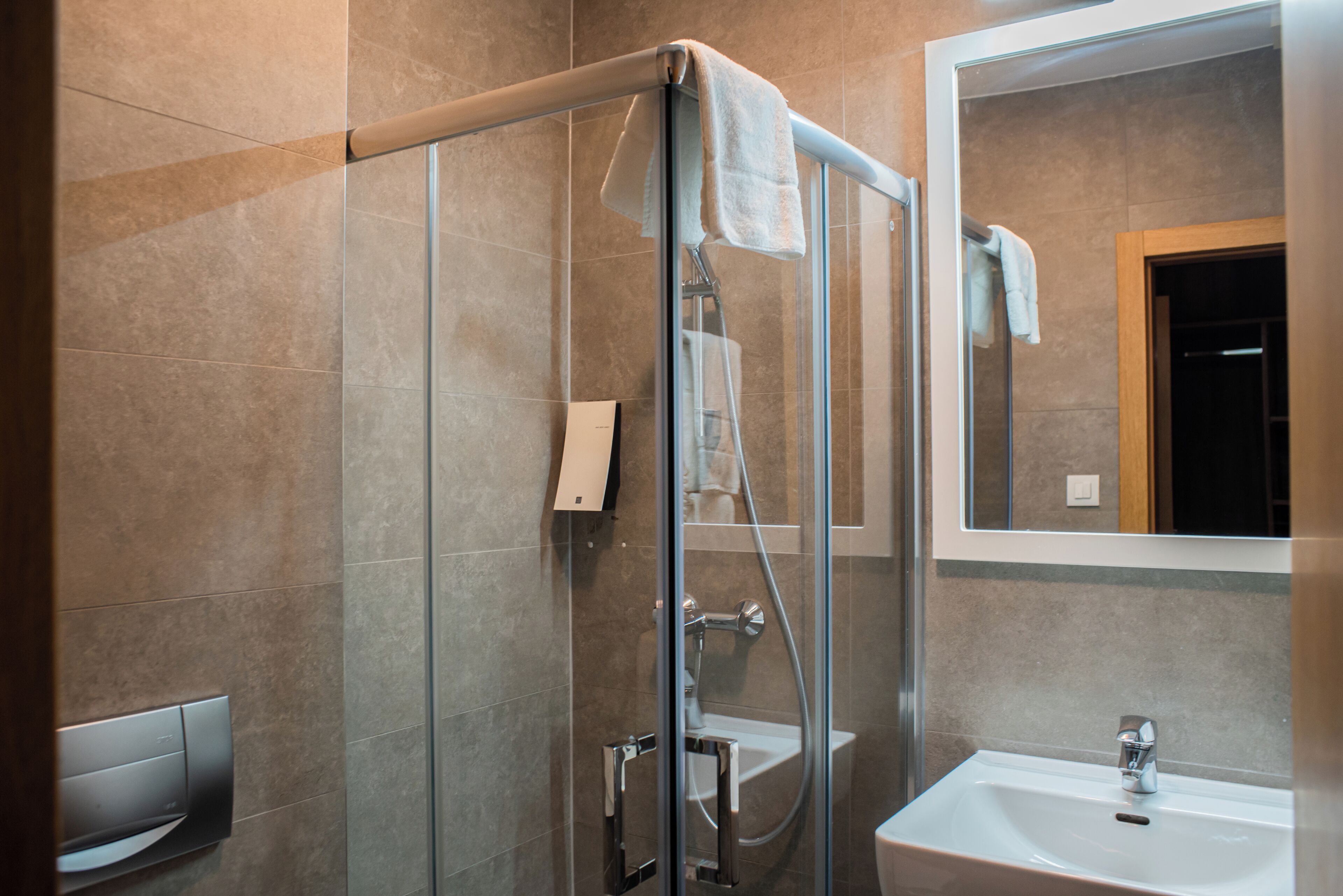 A modern bathroom with a glass shower enclosure, a sink, and a mirror.
