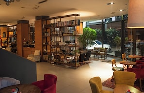 Ein modernes Interieur mit einer großen Bücherwand, bequemen Sitzmöglichkeiten und Blick ins Freie.