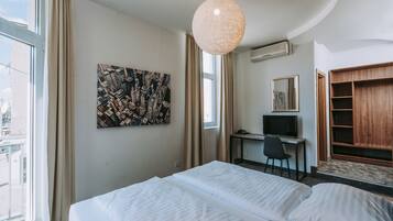 A hotel room with a bed, a desk with a computer, a television, and a wardrobe.