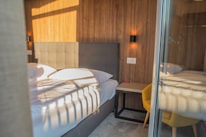 Ein modernes Schlafzimmer mit einem großen Bett, einem kleinen Nachttisch und einem Sessel.