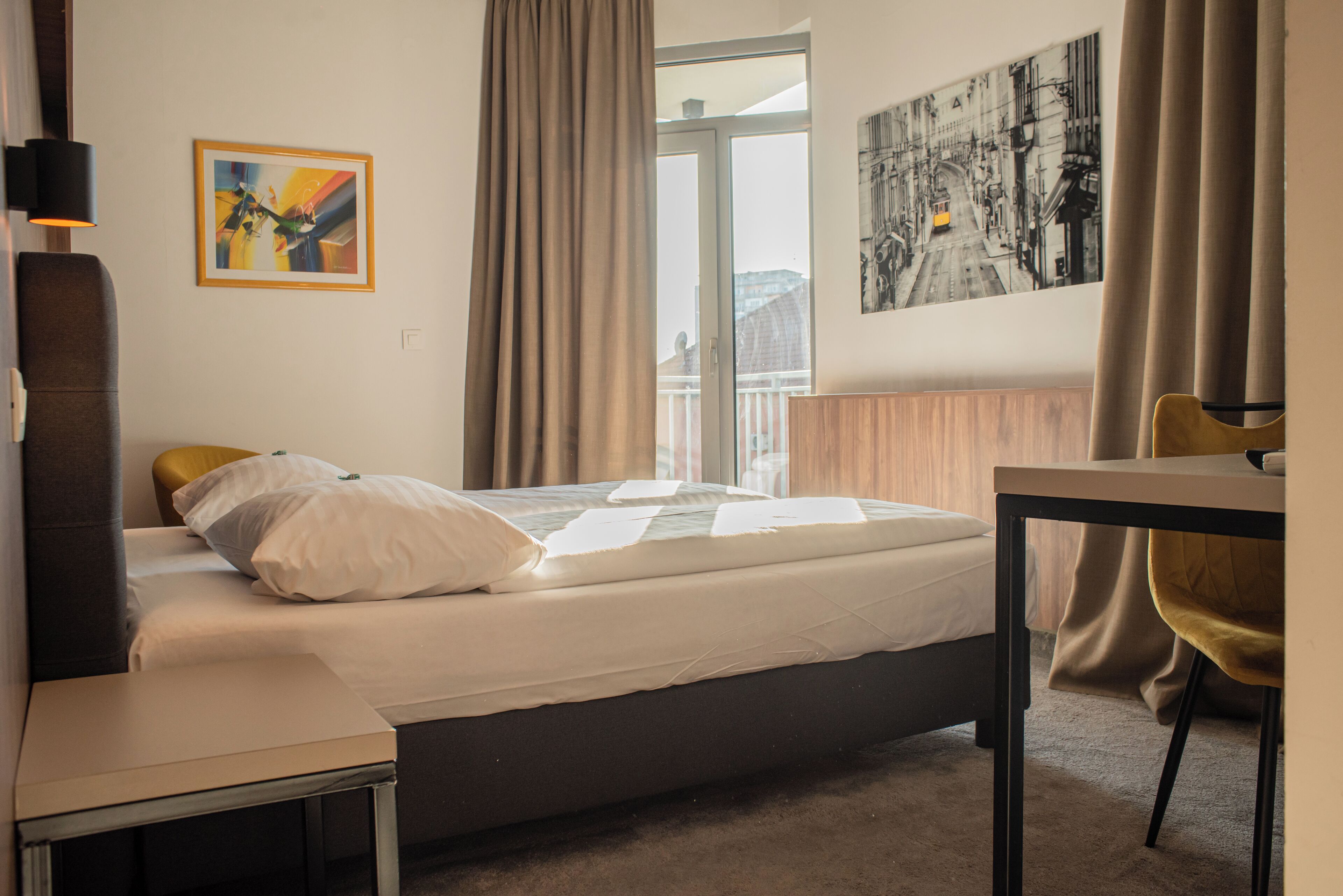 Una camera d'albergo con un letto, un tavolo, una sedia e una finestra con tende.