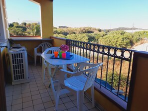 Un balcon avec une table, des chaises et un petit climatiseur.