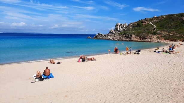 A beach with clear blue water, sandy shore, and rocky cliffs in the background. - Appartamenti Santa Teresa Gallura (Santa Teresa di Gallura)