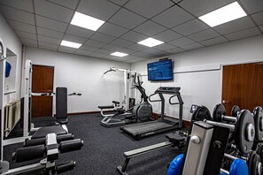 Un gimnasio con equipo de ejercicio, una cinta de correr y una pantalla instalada en la pared.