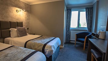 A hotel room with two beds, a desk, and a chair.