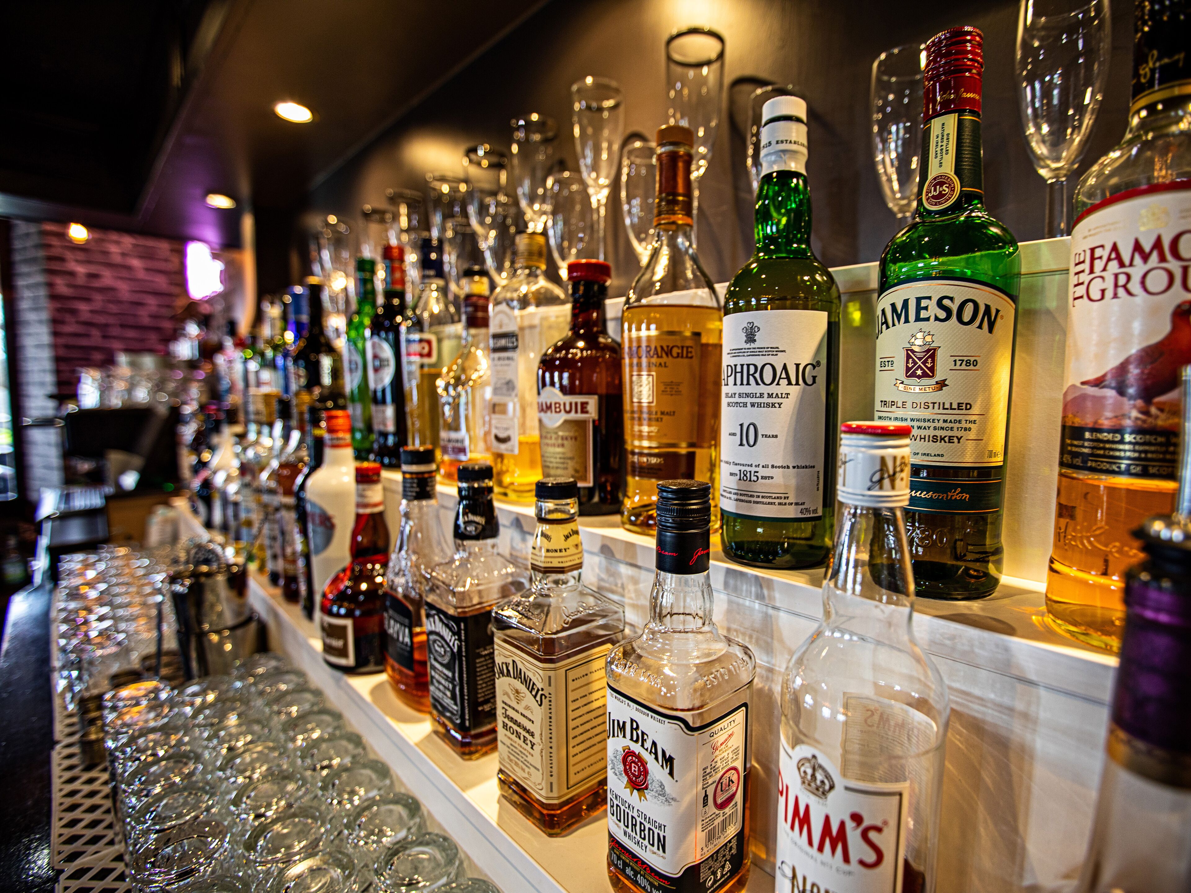Un bar avec une variété de bouteilles d’alcool et des verres.