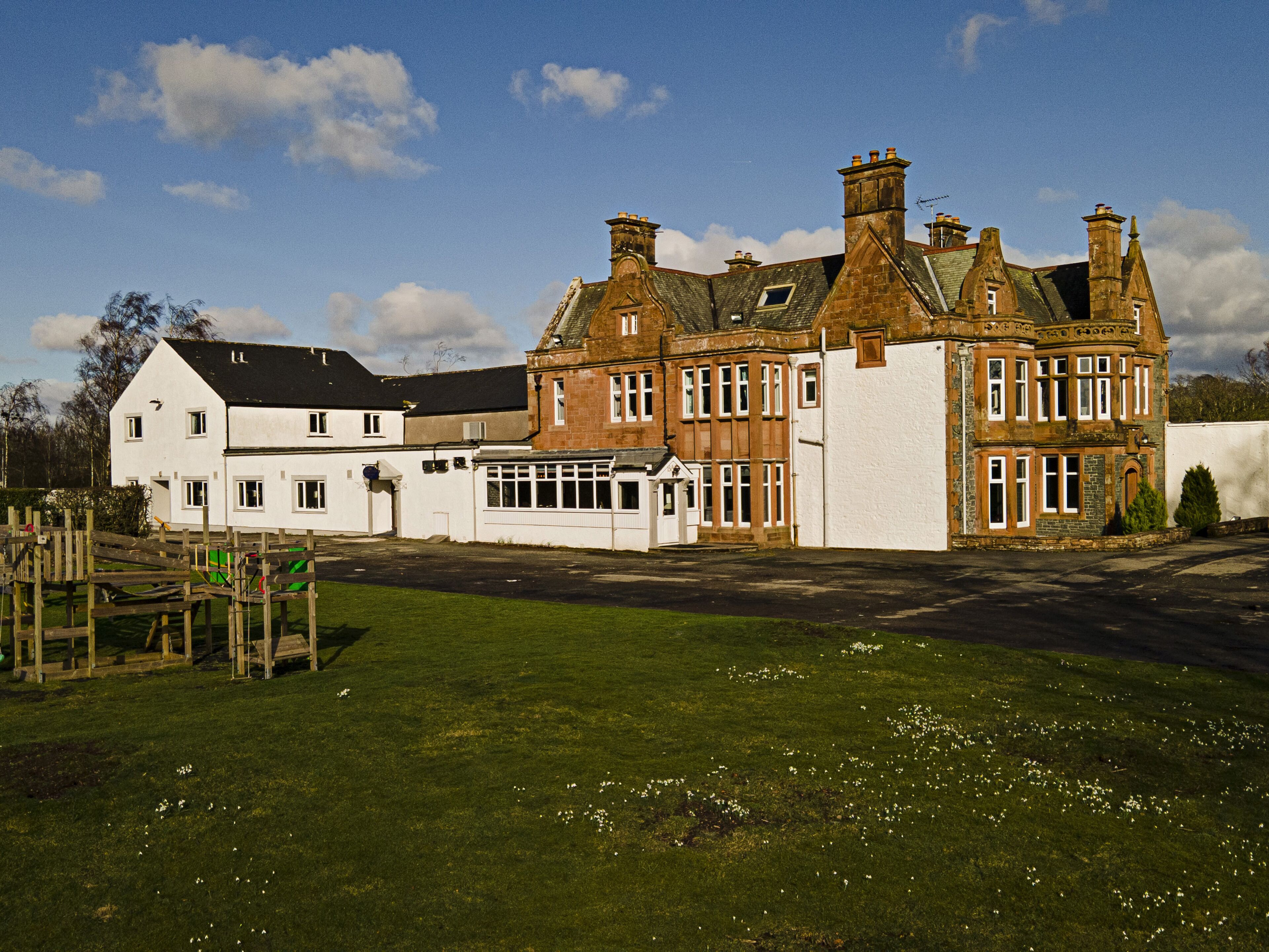 A large, historic building with multiple chimneys and a mix of brick and white walls.