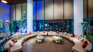 A modern lobby with a curved seating area, a large Christmas tree, and a view of the cityscape through large windows. - Amazing Hotel Sapa (Sa Pa)