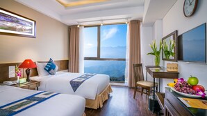 A hotel room with two beds, a desk with a chair, a clock, and a large window with a mountain view. - Amazing Hotel Sapa (Sa Pa)