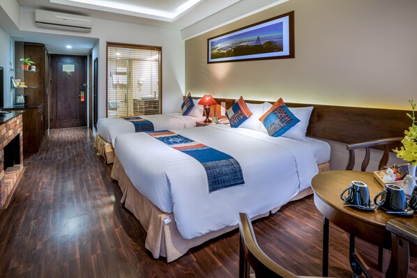 A hotel room with two beds, a desk, and a dining area.