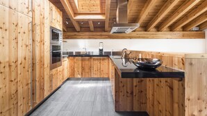 A modern kitchen with wooden cabinetry, a black countertop, and a skylight. - Ari Resort (Zermatt)