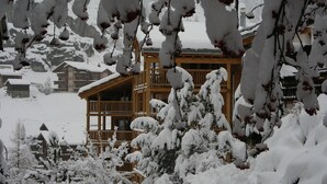 A wooden chalet with multiple balconies and snow-covered surroundings. - Ari Resort (Zermatt)