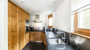 Une cuisine moderne avec des meubles en bois, des appareils électroménagers en acier inoxydable et un plan de travail noir.
