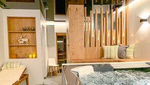 A modern spa room with a hot tub, wooden decor, and a relaxation area with a bed and pillows. - Ari Resort (Zermatt)