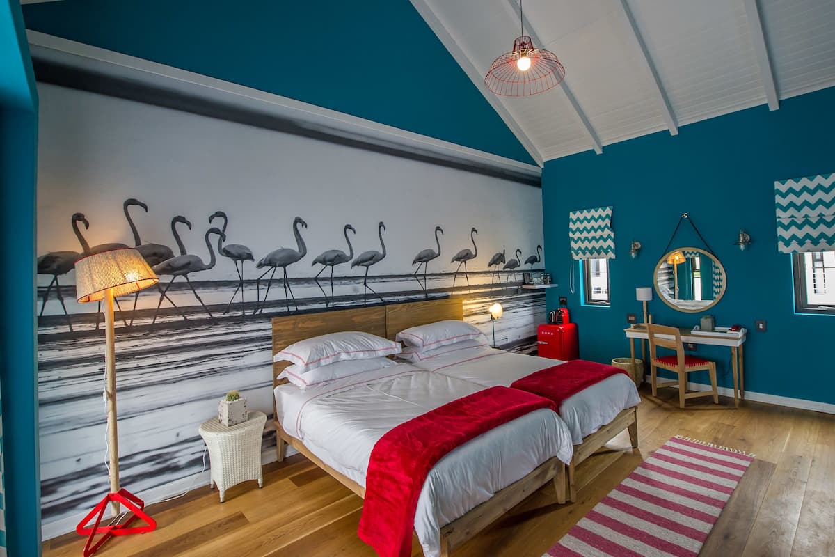 Een slaapkamer met een bed, een bureau, een stoel, een lamp en een wanddecoratie.