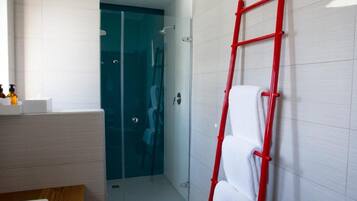 Un baño moderno con una bañera blanca, un tocador de madera, una cabina de ducha de vidrio y una escalera roja apoyada en la pared.