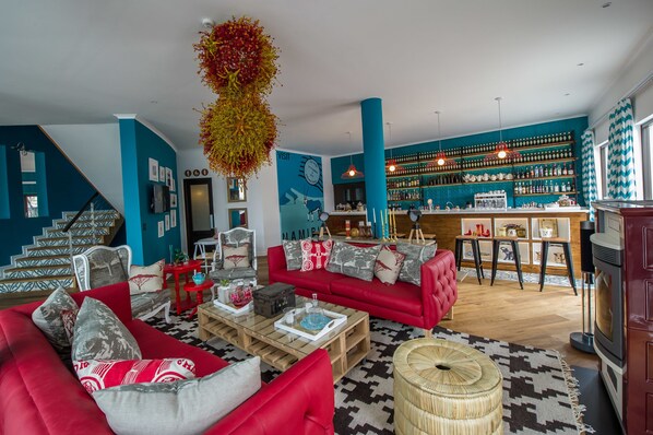 Una sala de estar moderna con sofás rojos, una mesa de centro y una zona de bar con estantes llenos de botellas.