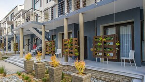 Un bâtiment moderne doté de nombreux balcons, d’un espace extérieur aménagé pour s’asseoir et de jardinières remplies de plantes.