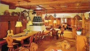 Un espace repas aménagé avec des meubles en bois, des lampes suspendues et une table centrale agrémentée d’un arrangement floral.