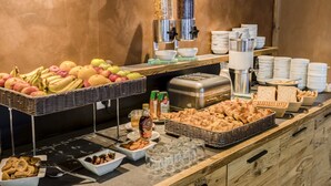 A buffet with various food items and beverages, including fruits, pastries, and a juice dispenser. - Saint Charles Hôtel & Spa (Val-Cenis)