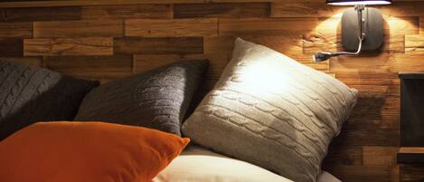 A bed with multiple pillows and a wall-mounted lamp.