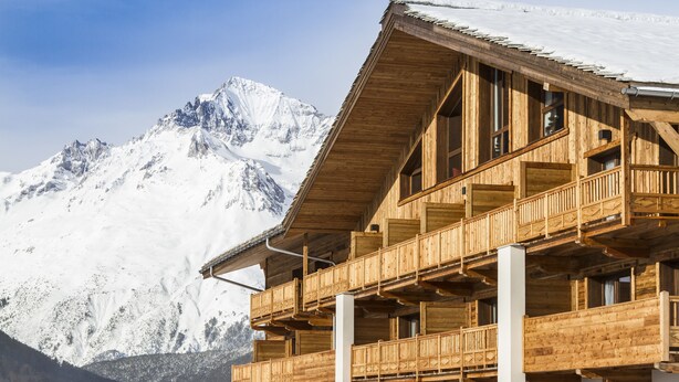 A wooden chalet with balconies overlooking a snow-covered mountain. - Saint Charles Hôtel & Spa (Val-Cenis)
