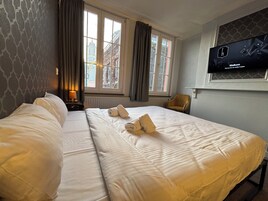 Een hotelkamer met twee bedden, een televisie aan de muur en een raam met gordijnen.
