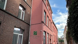 Una estrecha calle adoquinada con un edificio de ladrillo rojo que dice "Flandrina Hotel" a la derecha. Hay mesas y sillas en la acera.