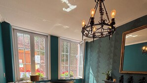 Una habitación con paredes color turquesa, un candelabro, dos sillones, una mesa y un espejo.