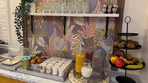 Un bufé de desayuno con diversos alimentos y bebidas, incluyendo yogur, huevos, frutas y una presentación de frutas.