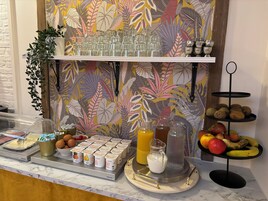 Een ontbijtbuffet met diverse etenswaren en drankjes, waaronder yoghurt, eieren, fruit en een fruitpresentatie.