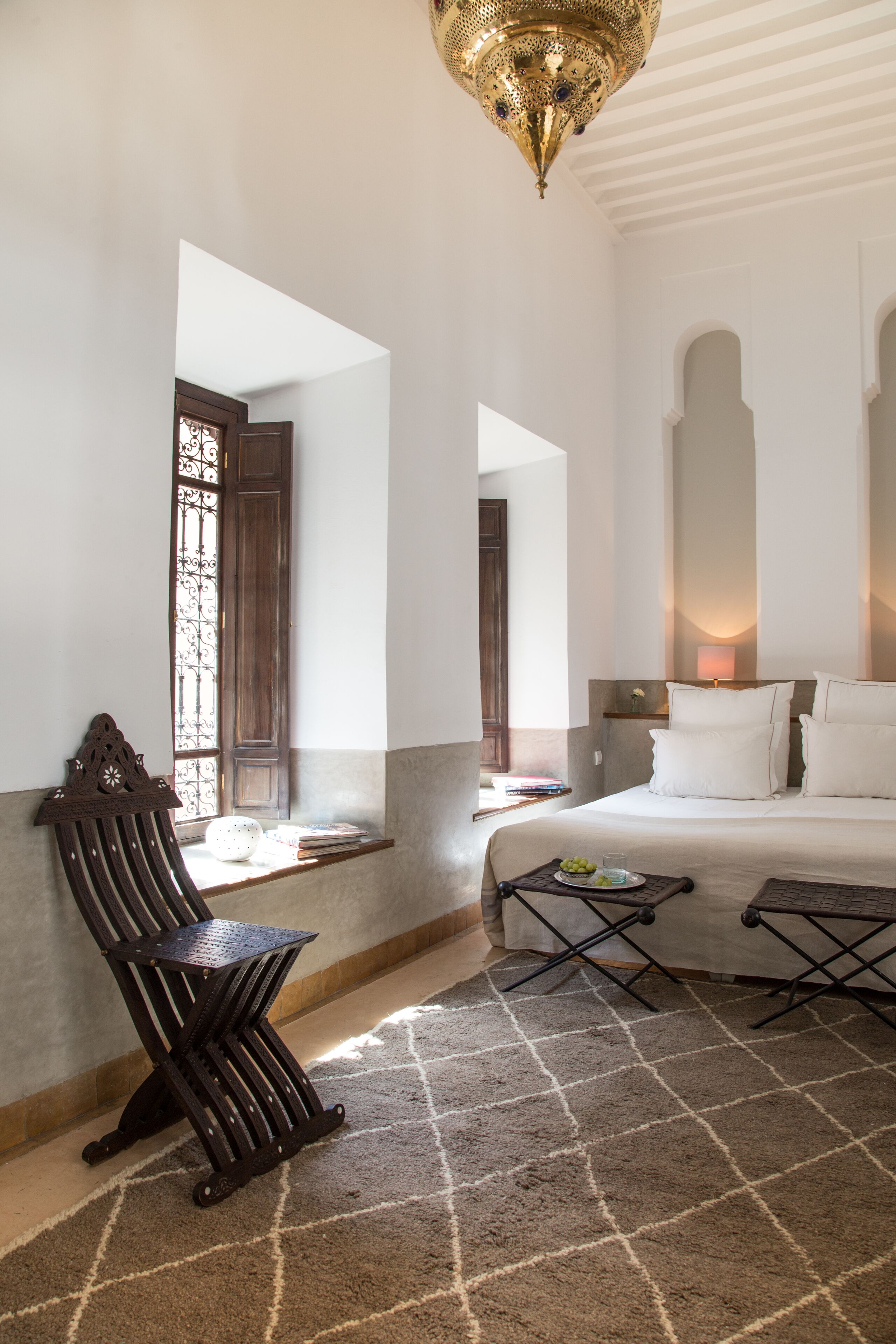 A bedroom with a bed, a nightstand, a lamp, a chair, and a window with a view.