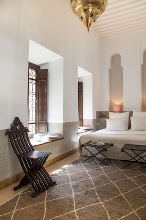 A bedroom with a bed, a nightstand, a lamp, a chair, and a window with a view.