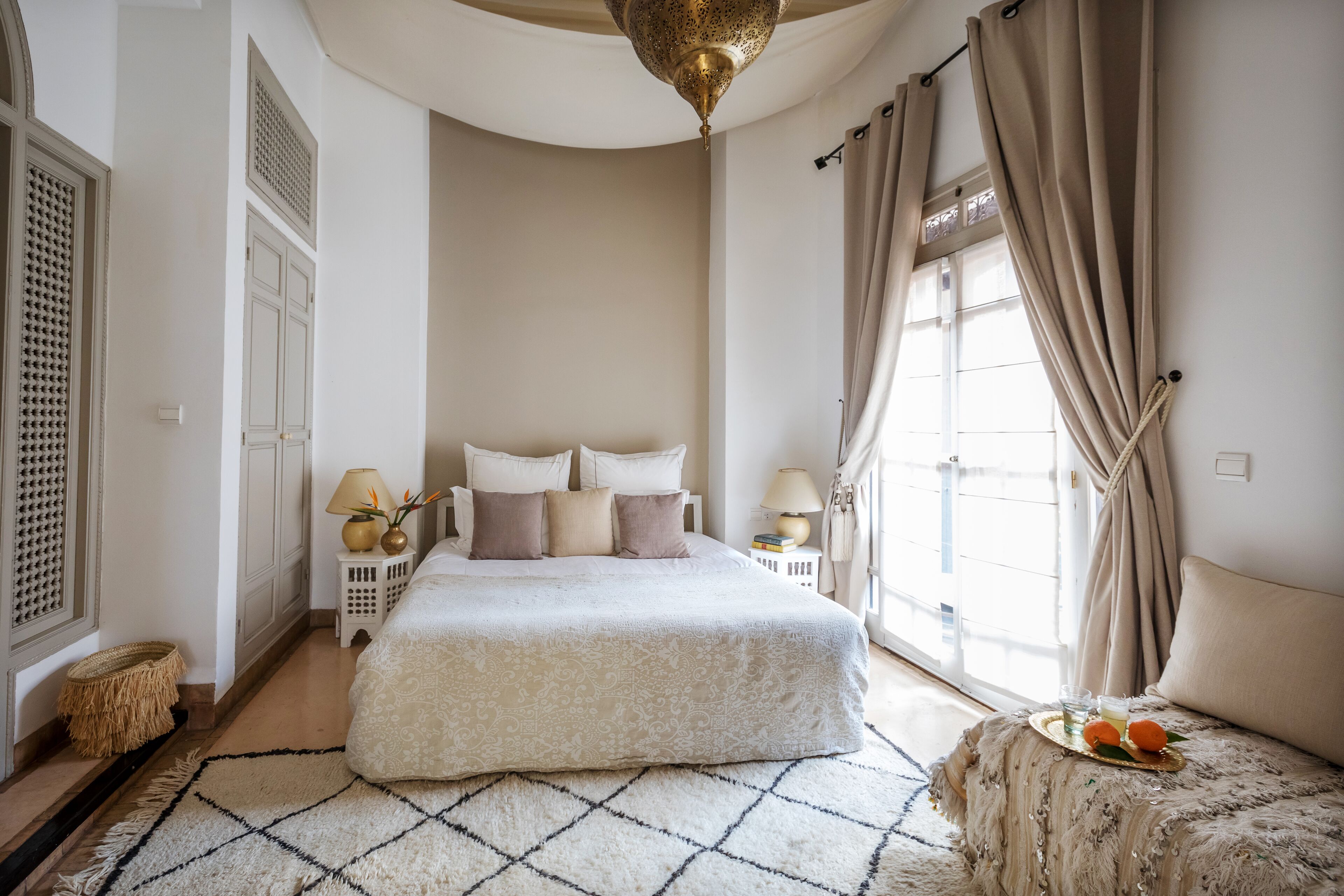 A spacious bedroom with a large bed, a small sofa, and a window with curtains.