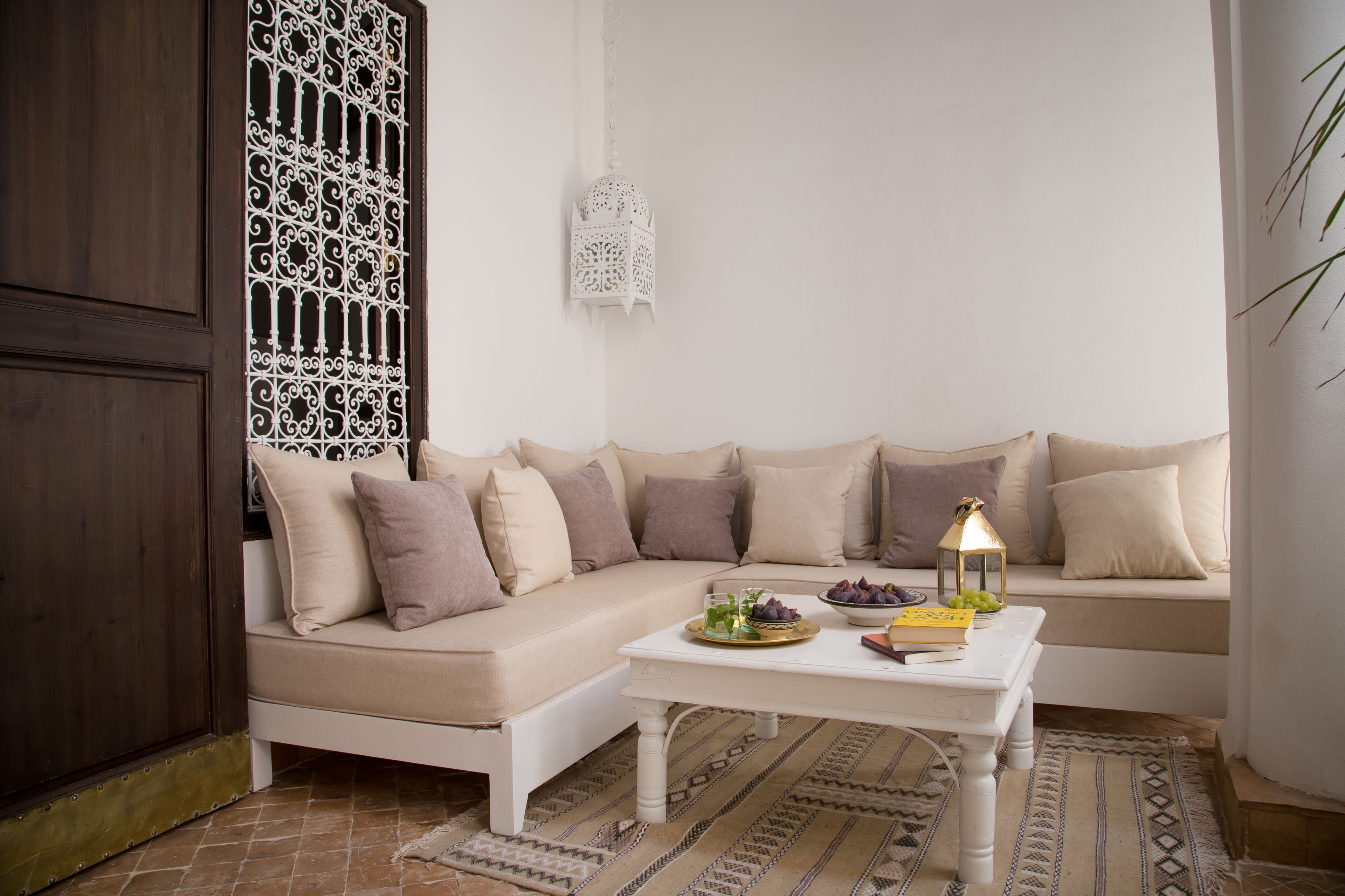 A cozy living room with a beige sofa, a white coffee table, and a patterned rug.