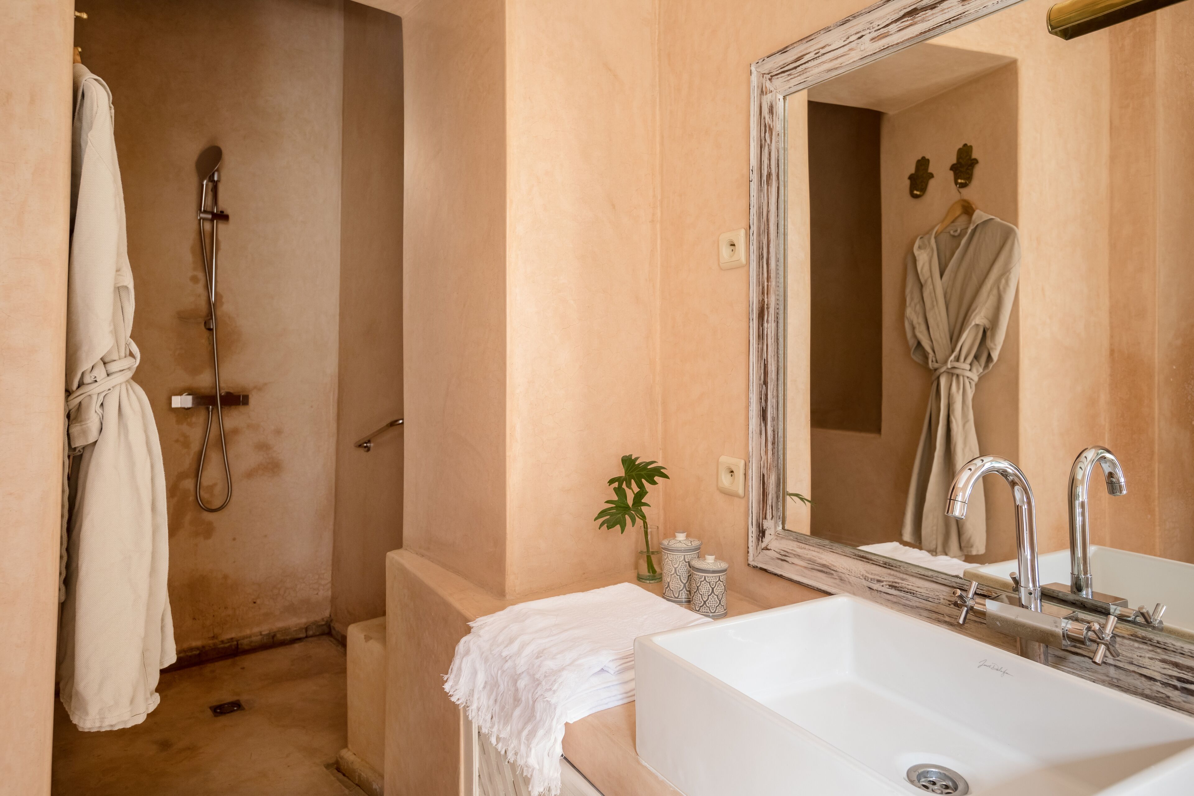 A bathroom with a bathtub, a sink, and a shower. There is a towel hanging on the wall and a plant on the counter.