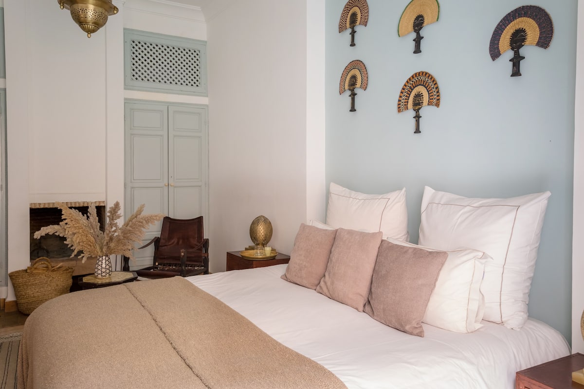Un dormitorio con una cama grande, una mesita de noche, una lámpara y un ventilador de pared.
