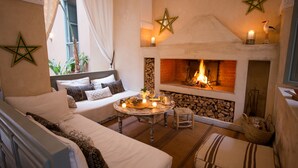 A cozy room with a fireplace, a sofa, a dining table with candles, and decorative stars on the walls. - Riad Olema et Spa (Marrakech)