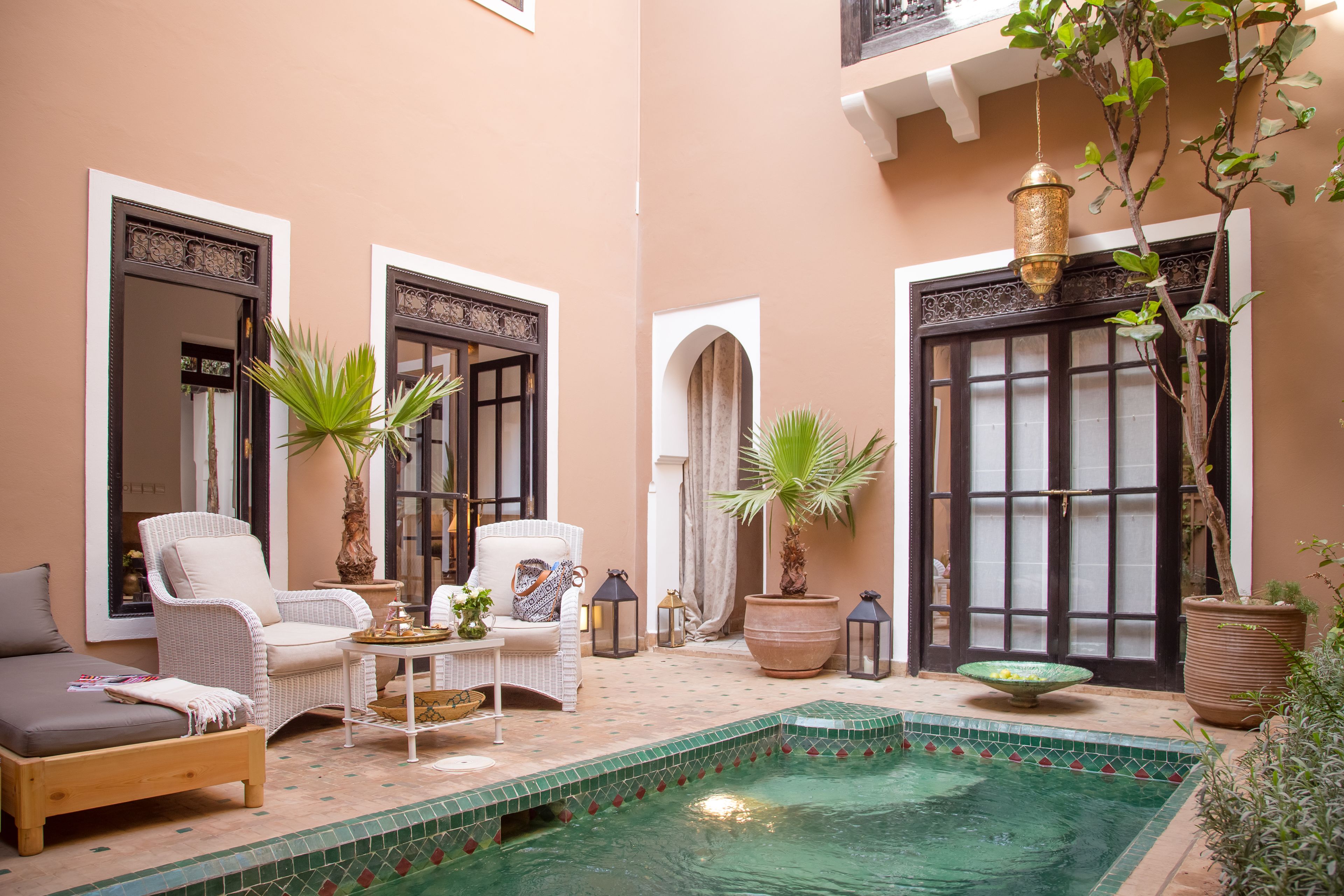 A cozy indoor pool area with a lounge chair, a small table, and potted plants.