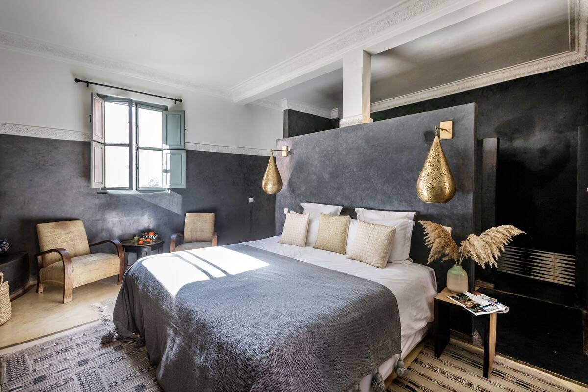 Un dormitorio moderno con una cama grande, una ventana y una pared oscura con textura.