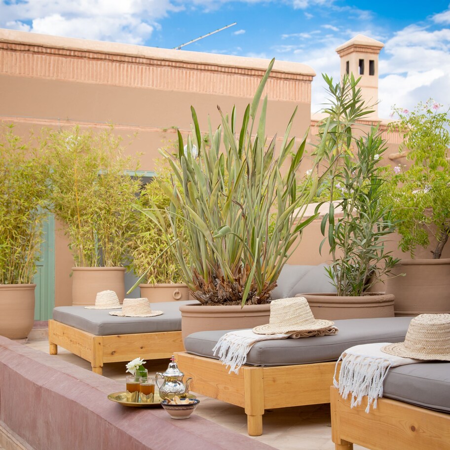 A cozy outdoor seating area with wooden furniture, potted plants, and a clear view of the sky.